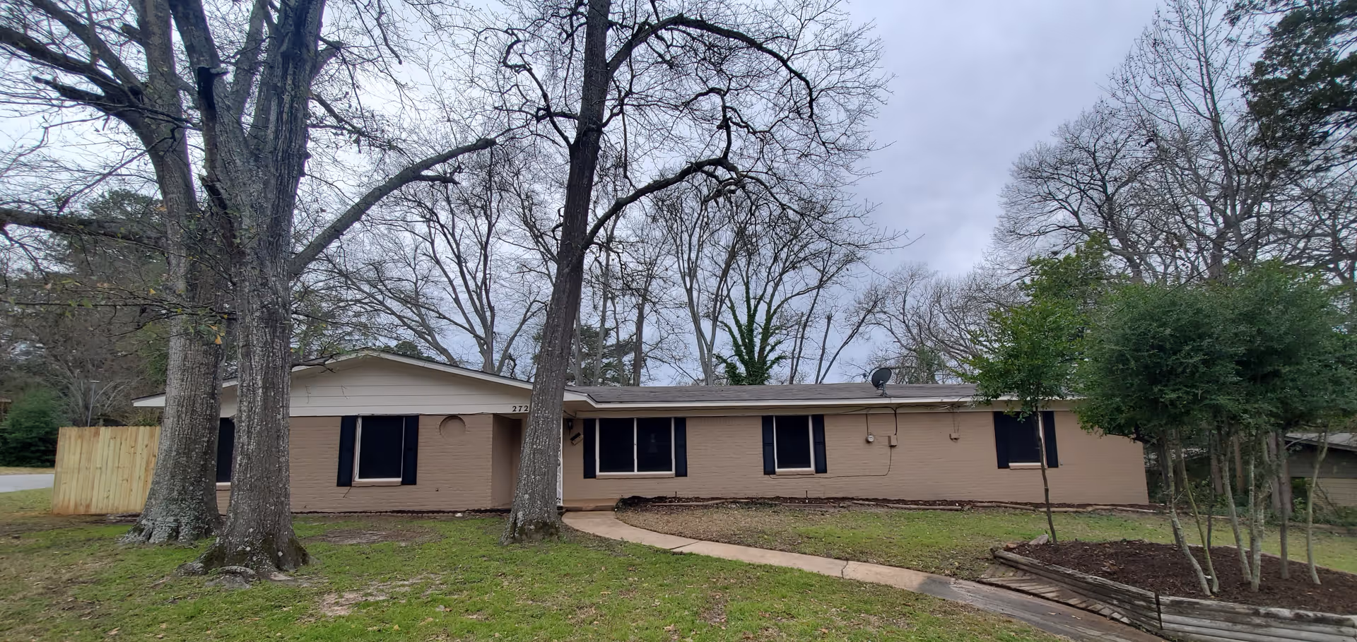 Exterior view of a single-story brick care facility with trees and a walkway.