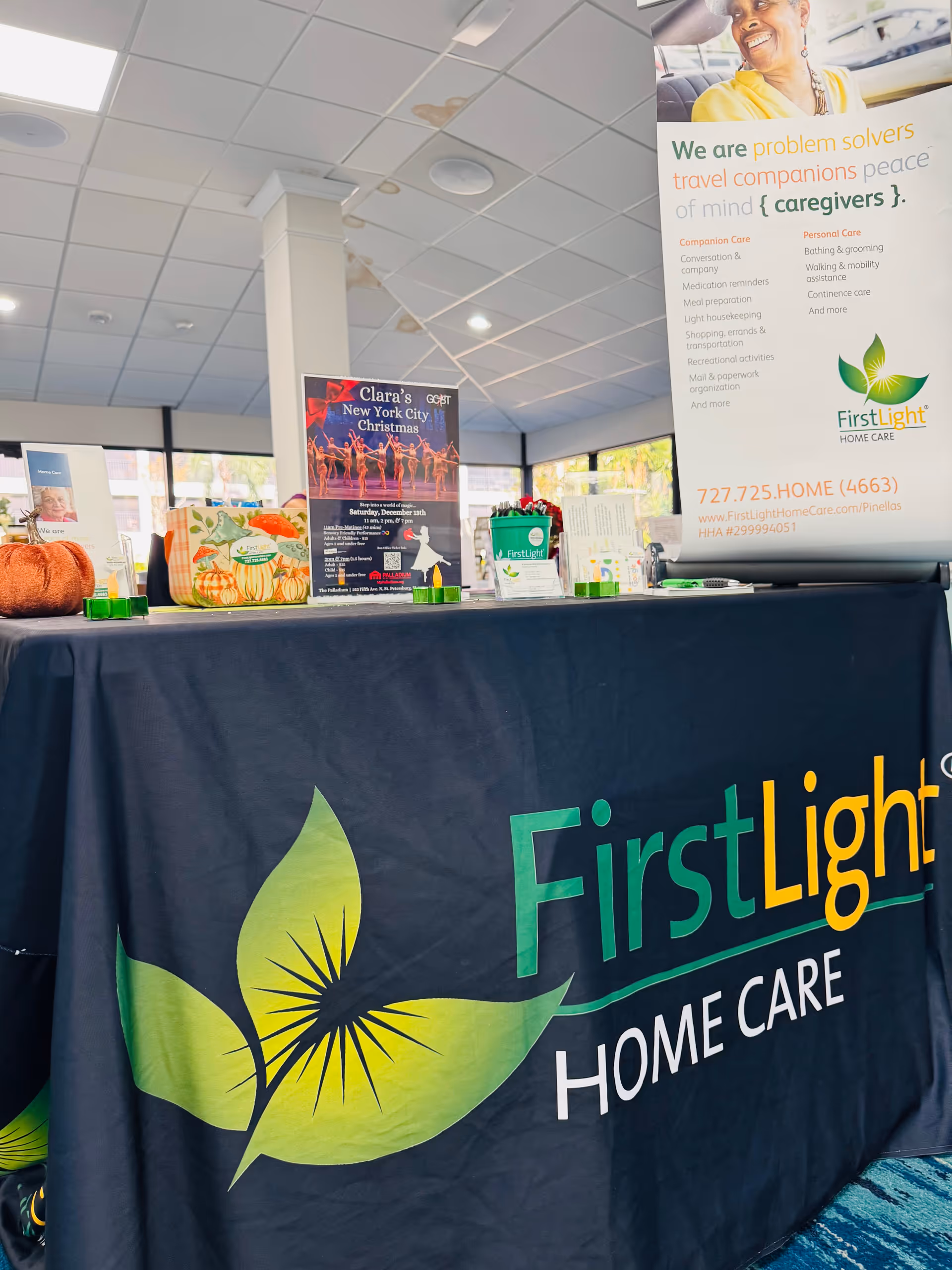 Indoor display area with a table draped in a FirstLight Home Care banner and signage.