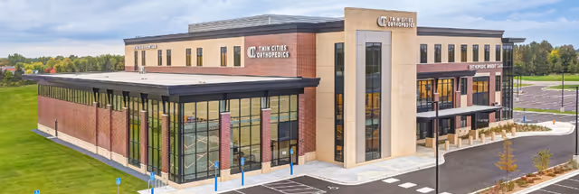 Exterior view of Plymouth Orthopedic Surgery Center, a modern brick building with glass windows.