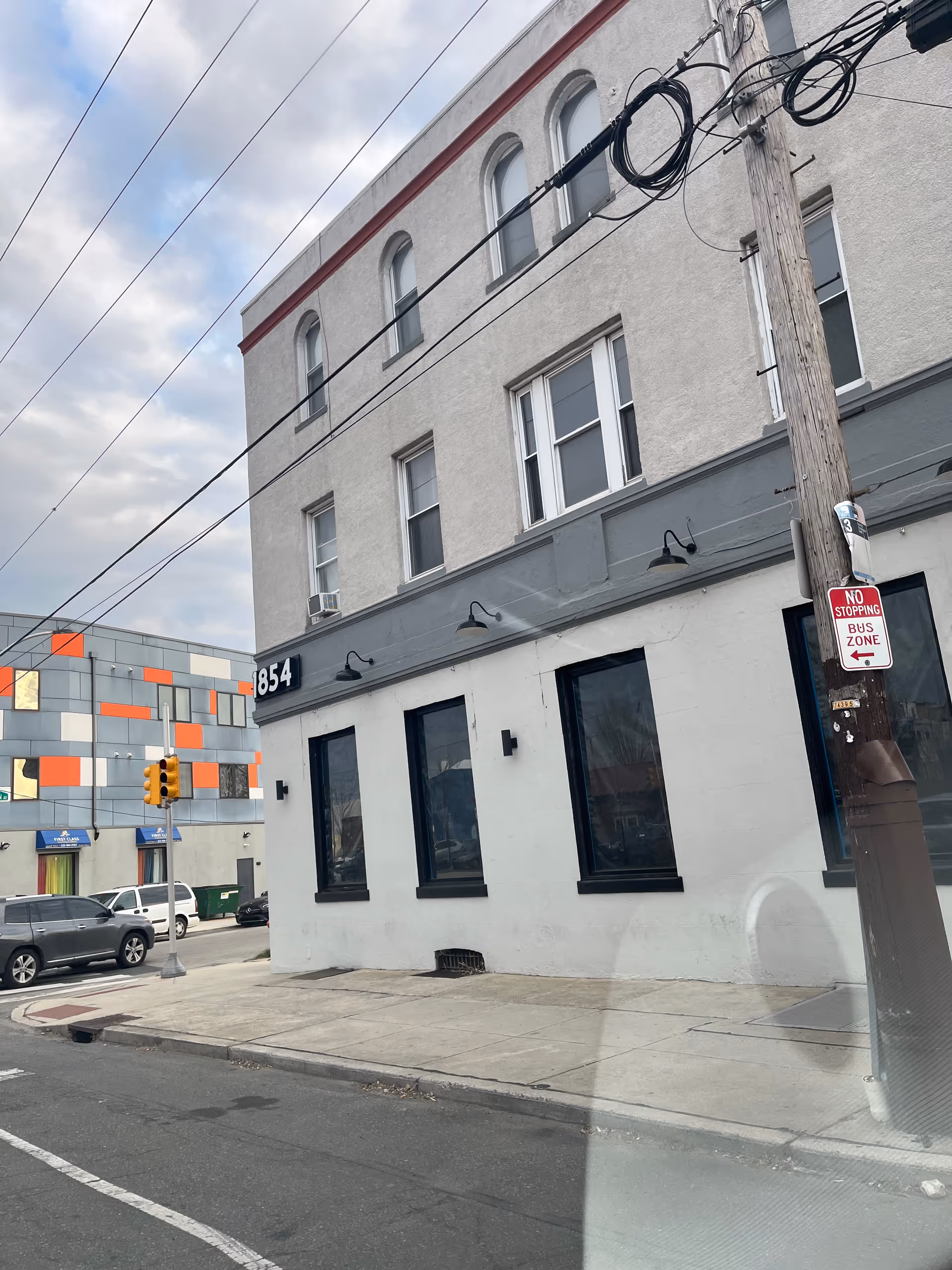 Front view of a three-story white building on a city street with utility lines.