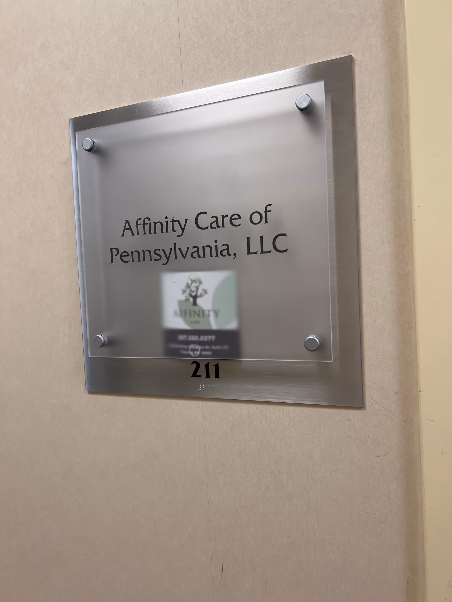 Metal wall plaque displaying Affinity Care of Pennsylvania, LLC and room 211.