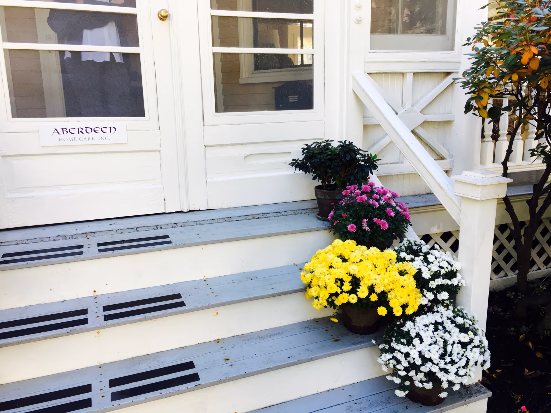 White exterior entrance with steps, potted flowers, and a sign reading Aberdeen Home Care, Inc.