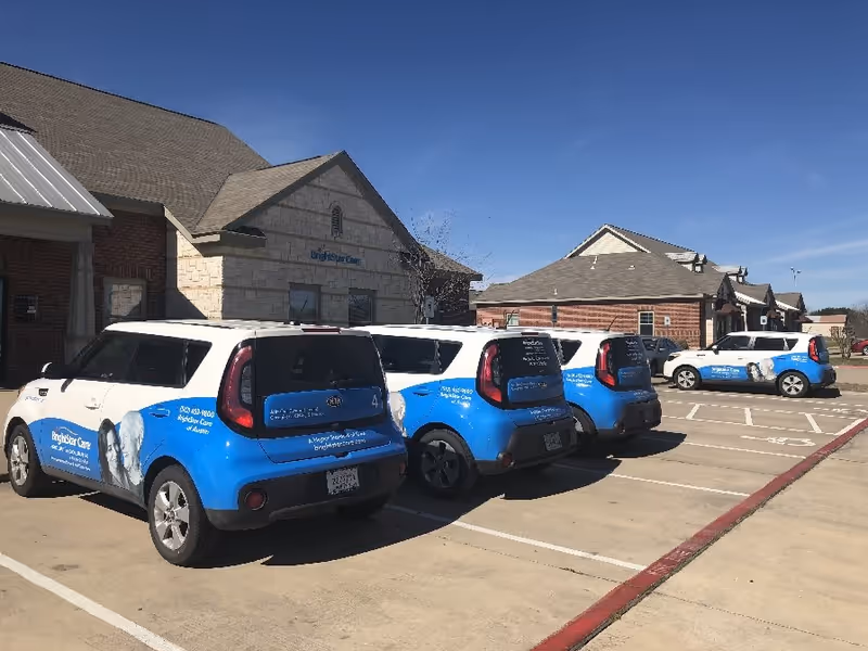 BrightStar Care Austin vans lined up in front of a brick facility.