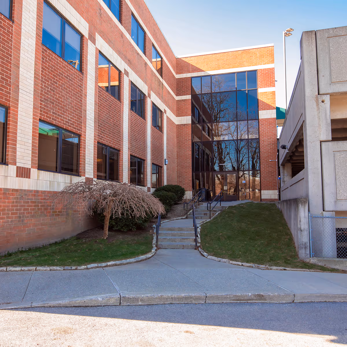 Exterior view of a brick building with a large glass entrance and steps.