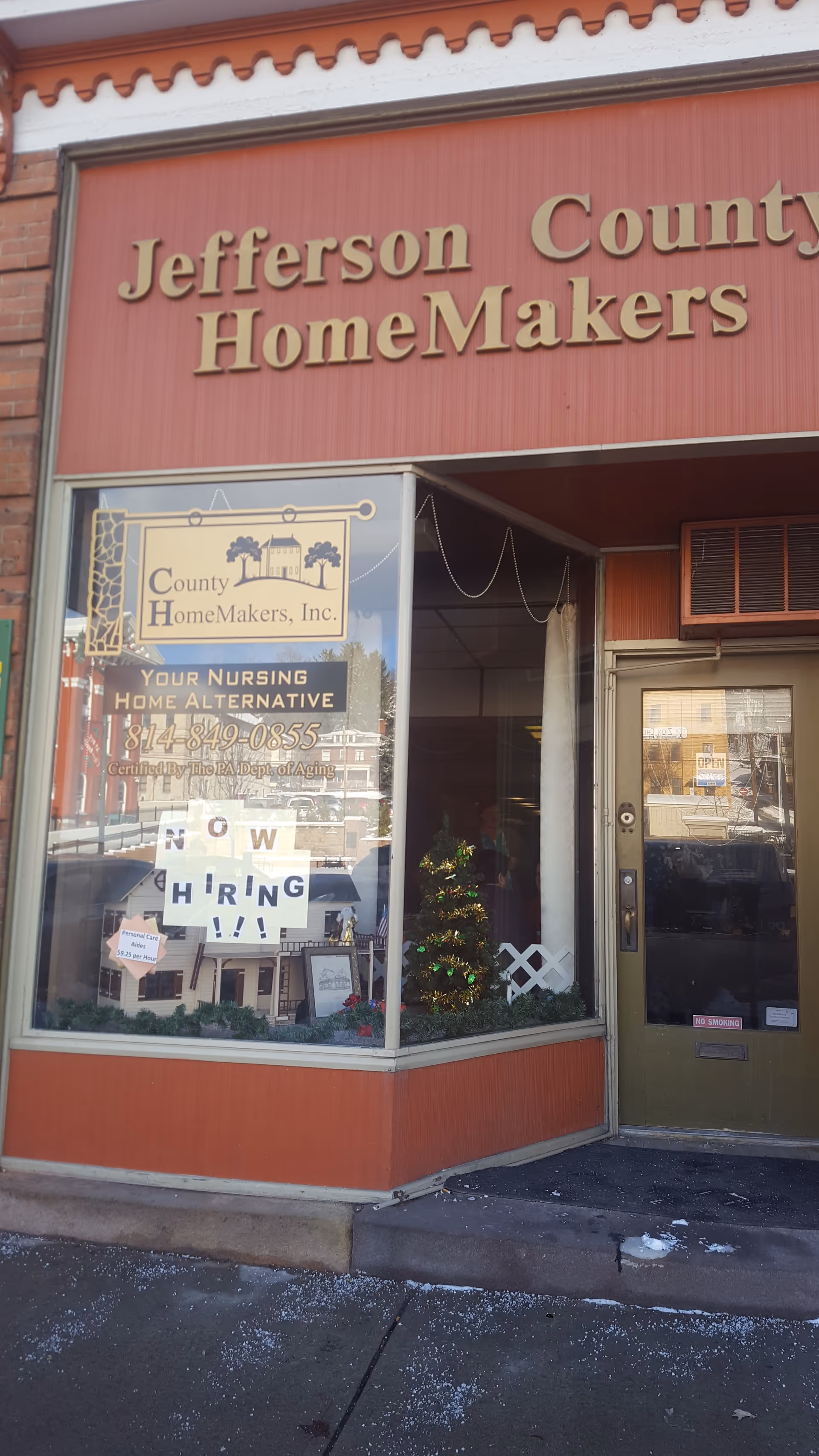 Storefront of a red building with Jefferson County HomeMakers sign and hiring notices in window.