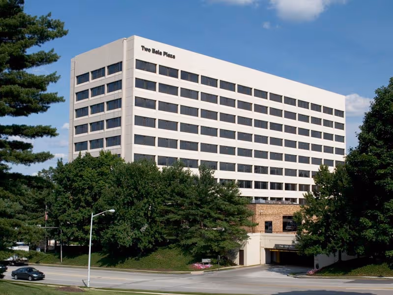 White multi-story building with many windows and a 'Two Bella Plaza' sign.