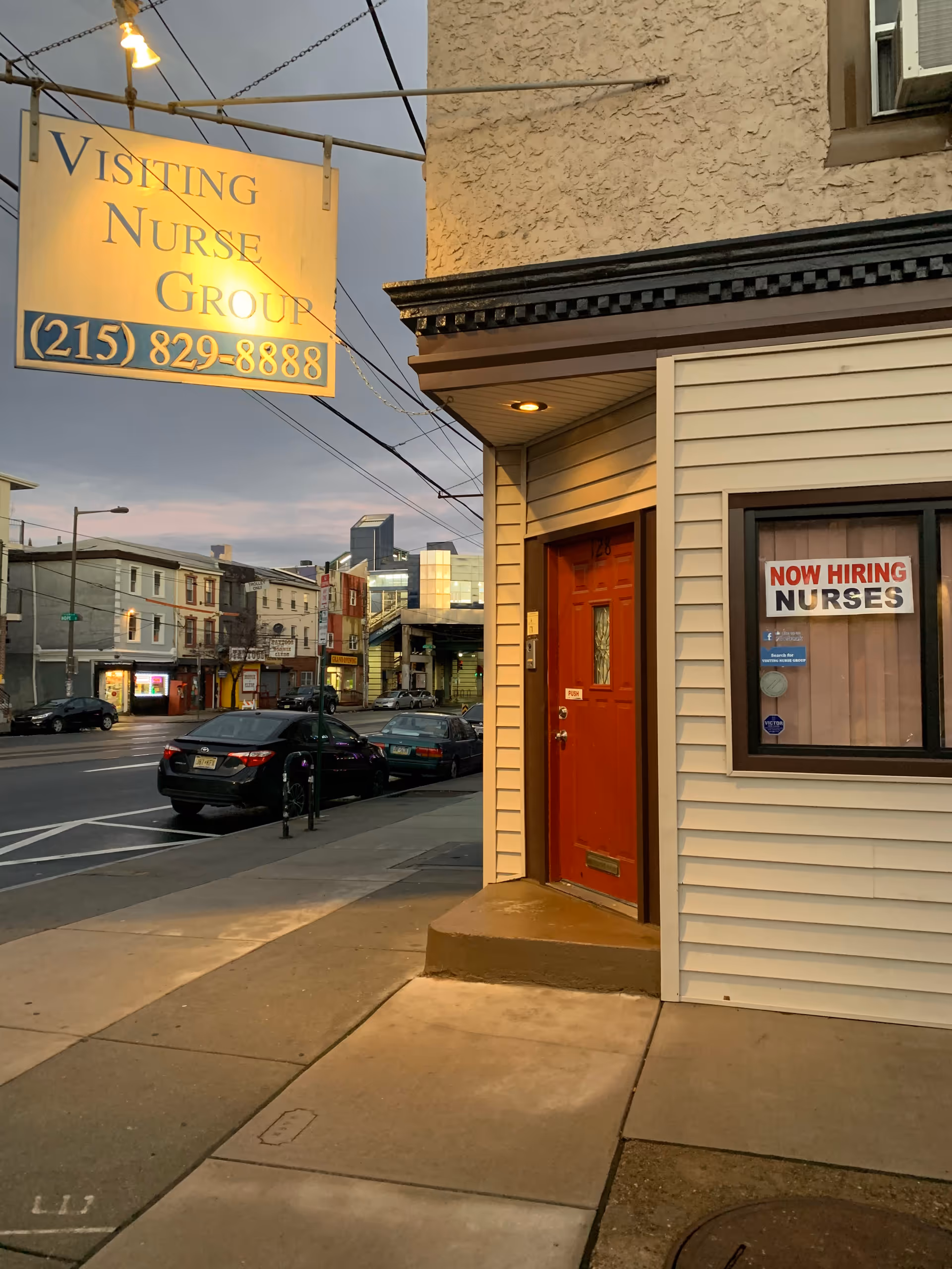 Exterior street view showing a building with a Visiting Nurse Group sign and window notice.