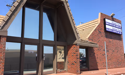 Brick building with tall glass entrance and a sign reading Human Touch Home Health.