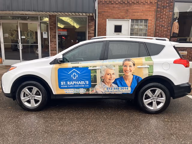 White SUV with St. Raphael's Home Care Services LLC wrap and two smiling people.