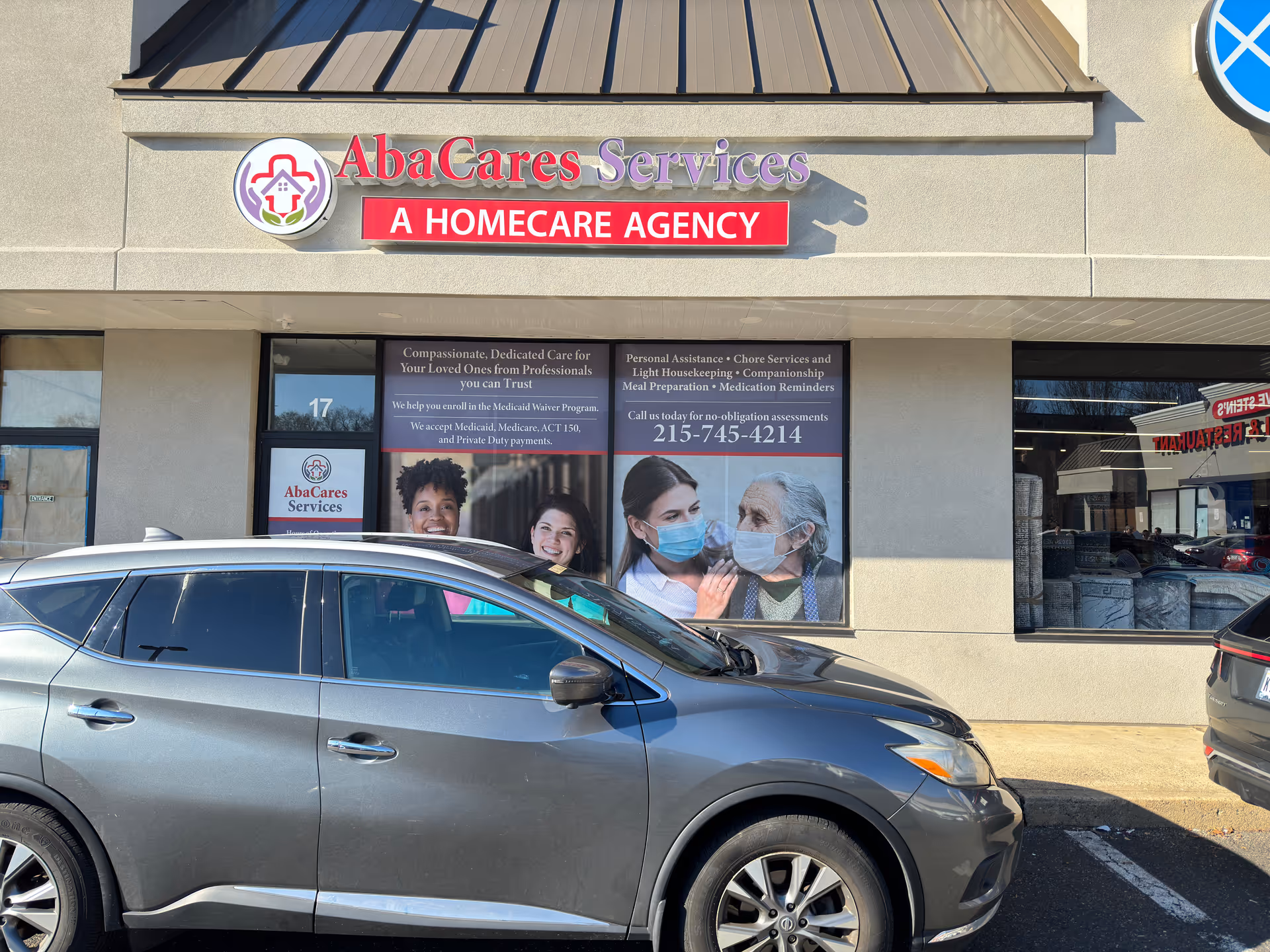 Exterior view of AbaCares Services storefront with a red A Homecare Agency sign and parked car.
